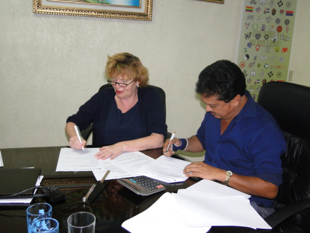a man and a woman sitting at a table while doing paperwork