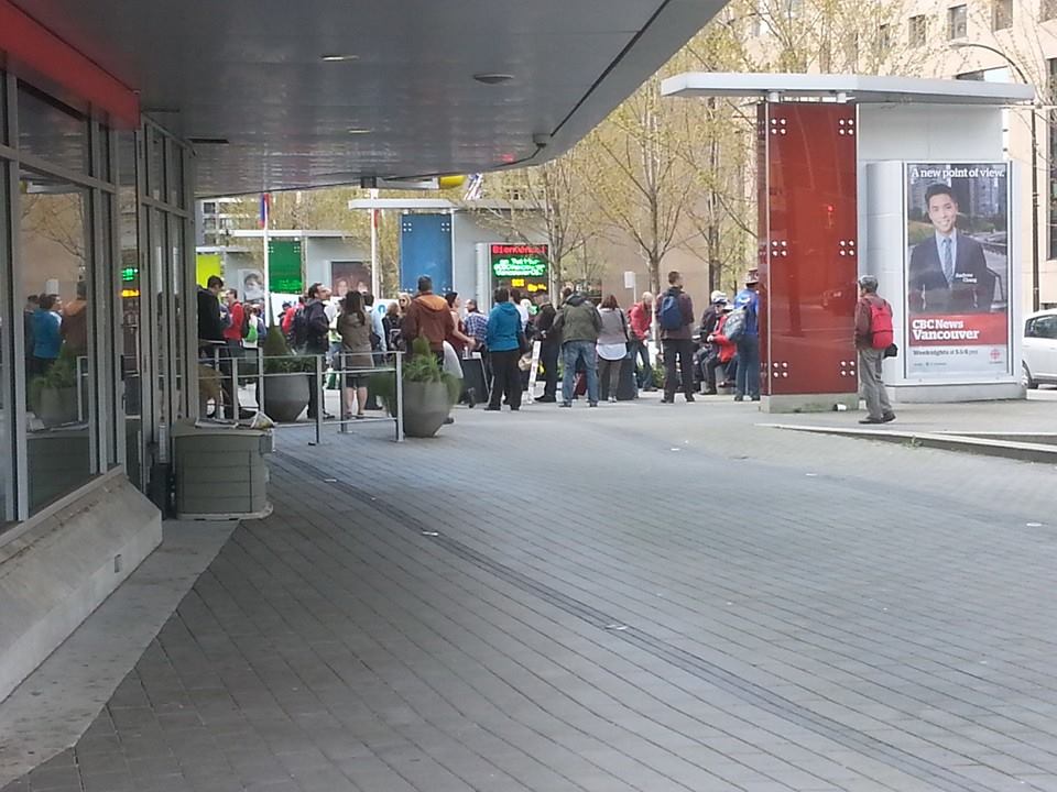 many people walking on the sidewalk near shops and a street