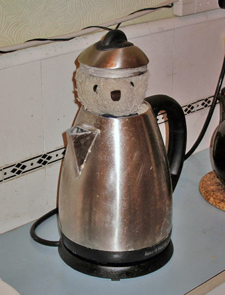 an antique electric tea kettle with bear head cutouts