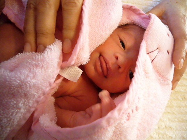 a baby being held up in pink blankets