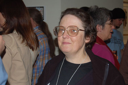 a woman wearing glasses stands smiling with other people
