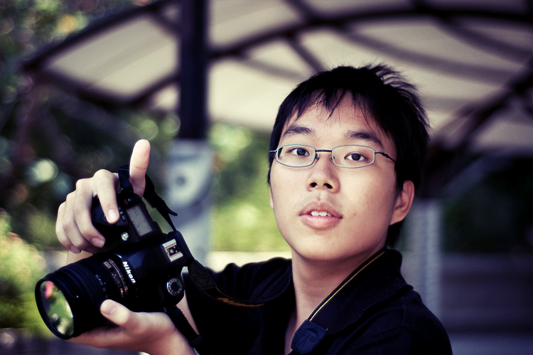 a man with glasses is holding up a camera