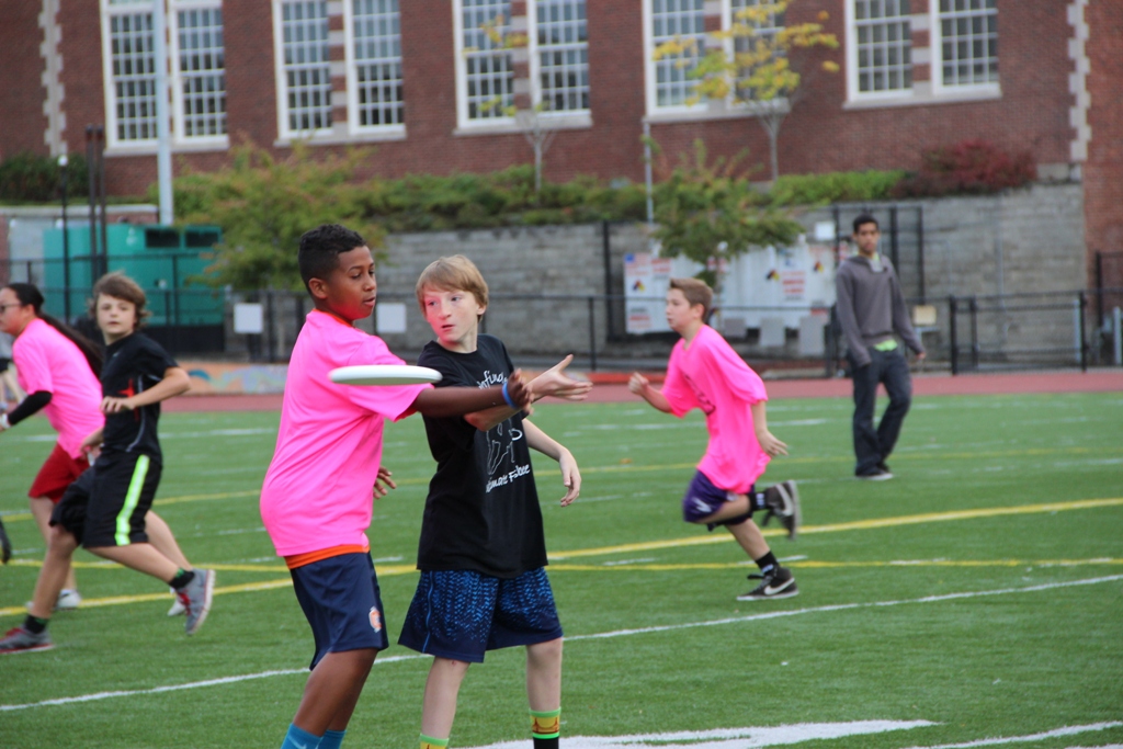 young children are playing frisbee on the soccer field