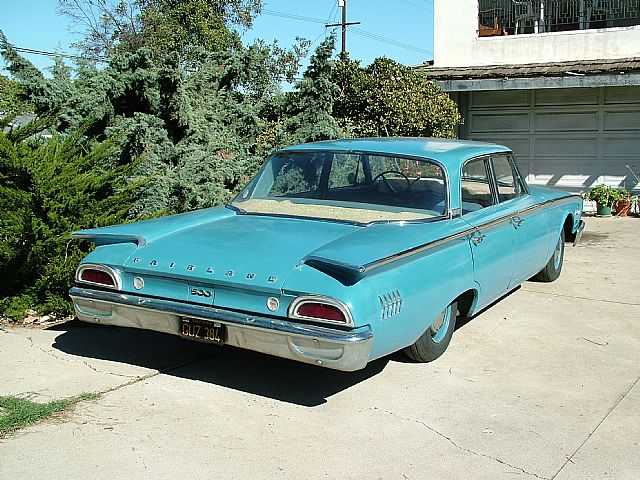 an old blue car parked in a driveway