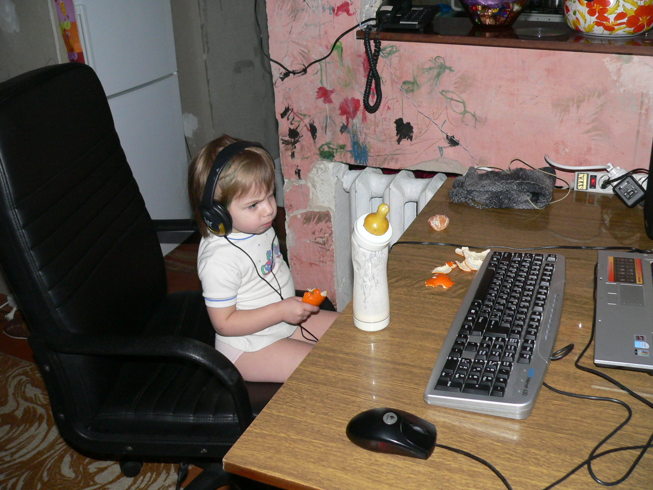 a little girl that is sitting next to a keyboard