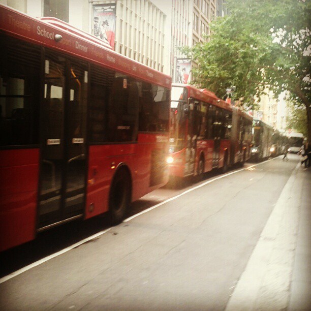 a couple of big red buses that are going down the street