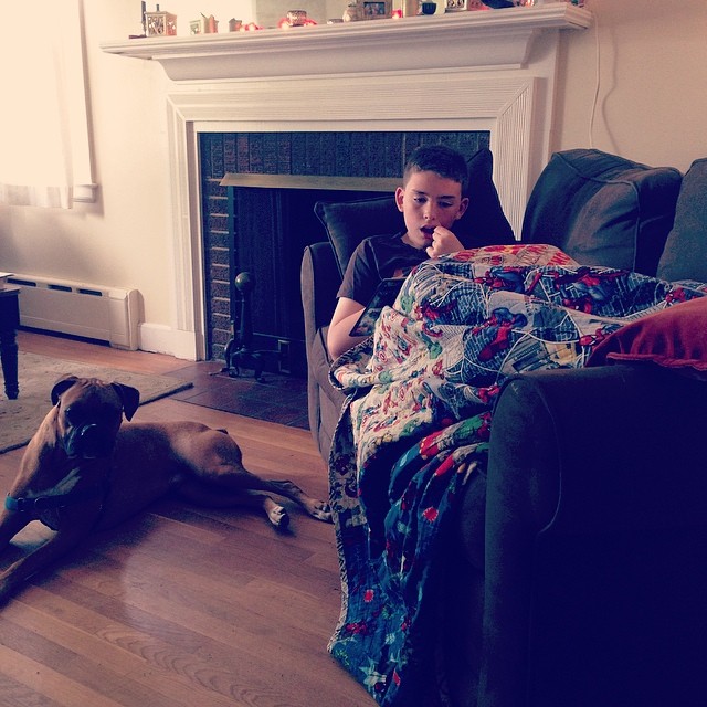 a person laying down on a couch next to a dog