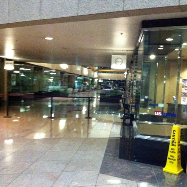 a glass door inside of a lobby with yellow caution signs