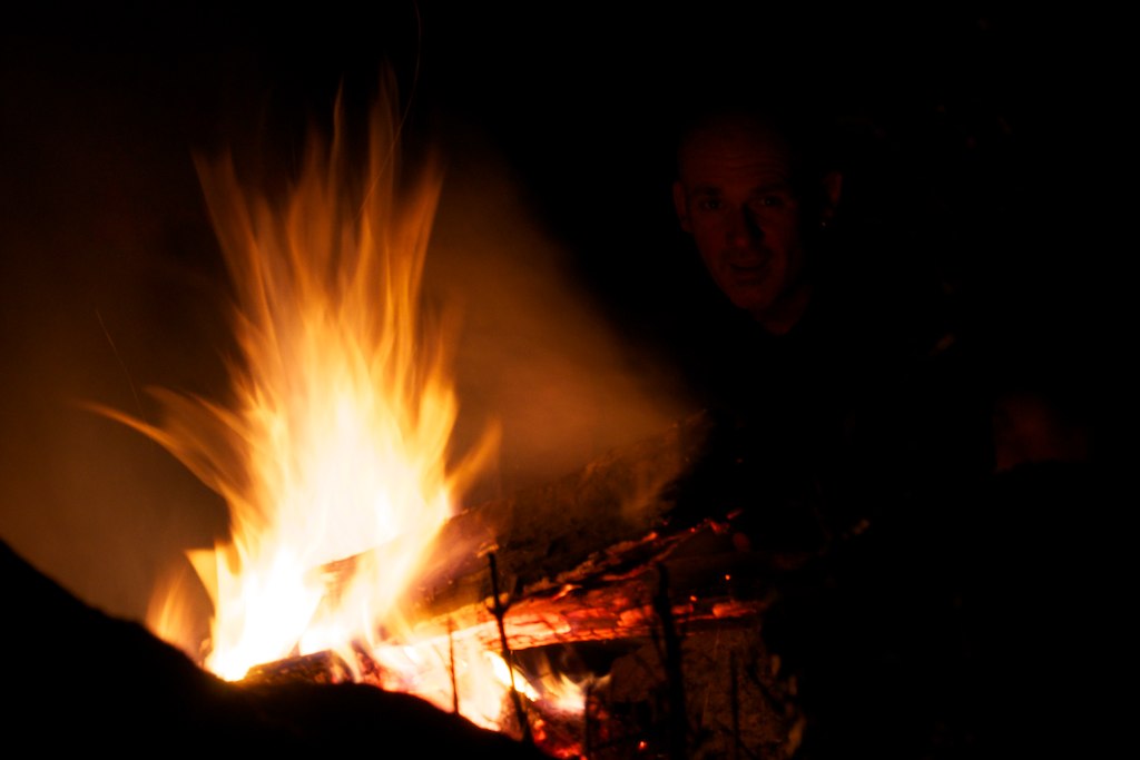 a man sitting near a bonfire in the dark