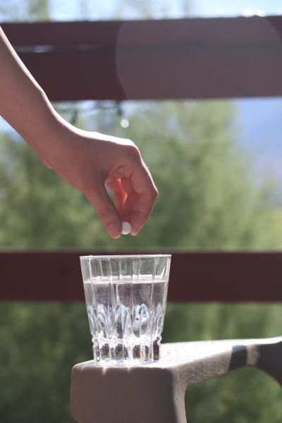 someone is holding a pill in their glass