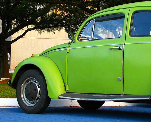 an old green beetle parked in front of a building