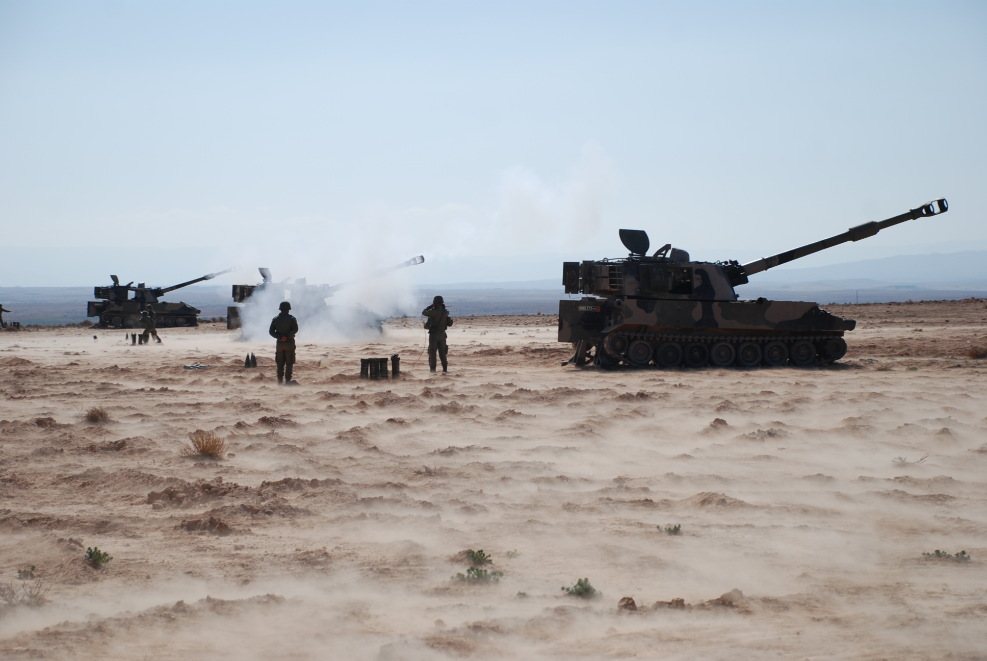 two men and two dogs looking at a tank