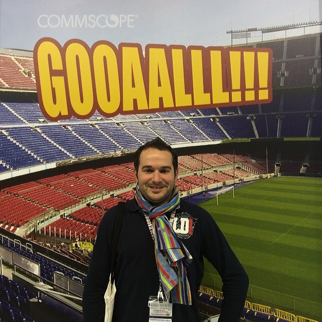 man posing in front of large stadium sign with words