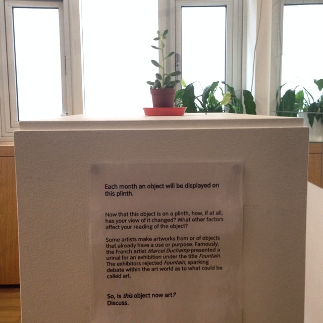 a sign with an empty piece of paper attached to it and some plants