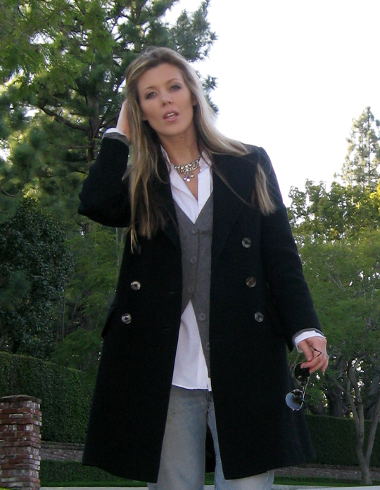 a woman in a coat is posing on the sidewalk