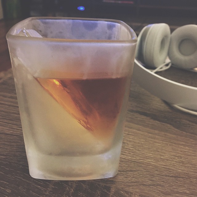 there is a glass with some drink and headphones