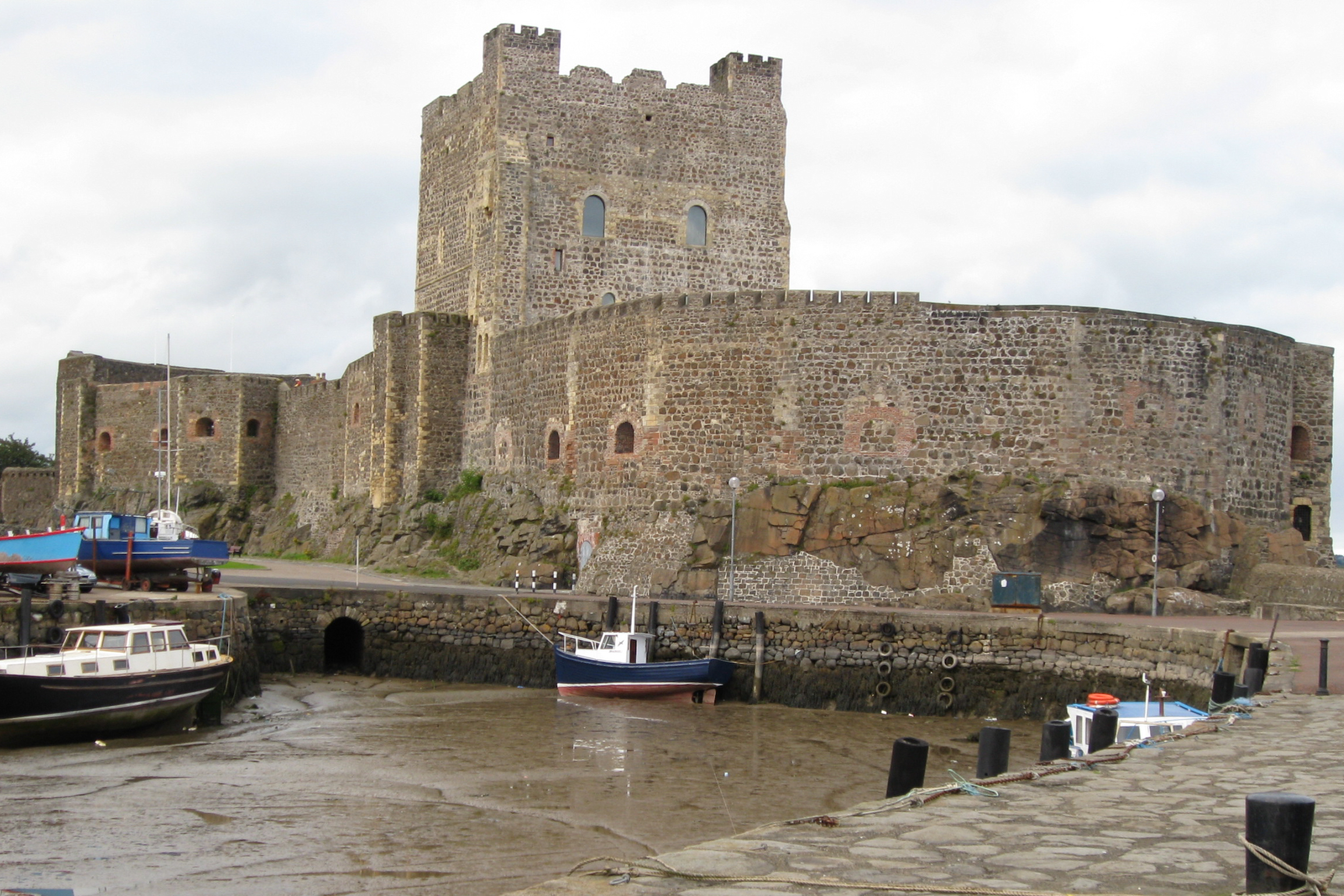 a large stone castle with boats parked in front