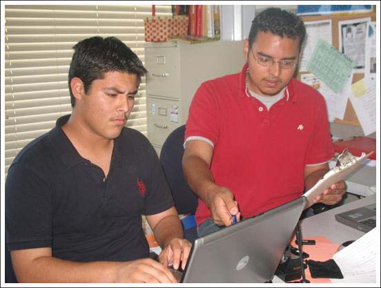 two men working on an open laptop computer