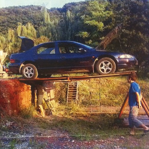 car on top of large barrel, in outdoor setting