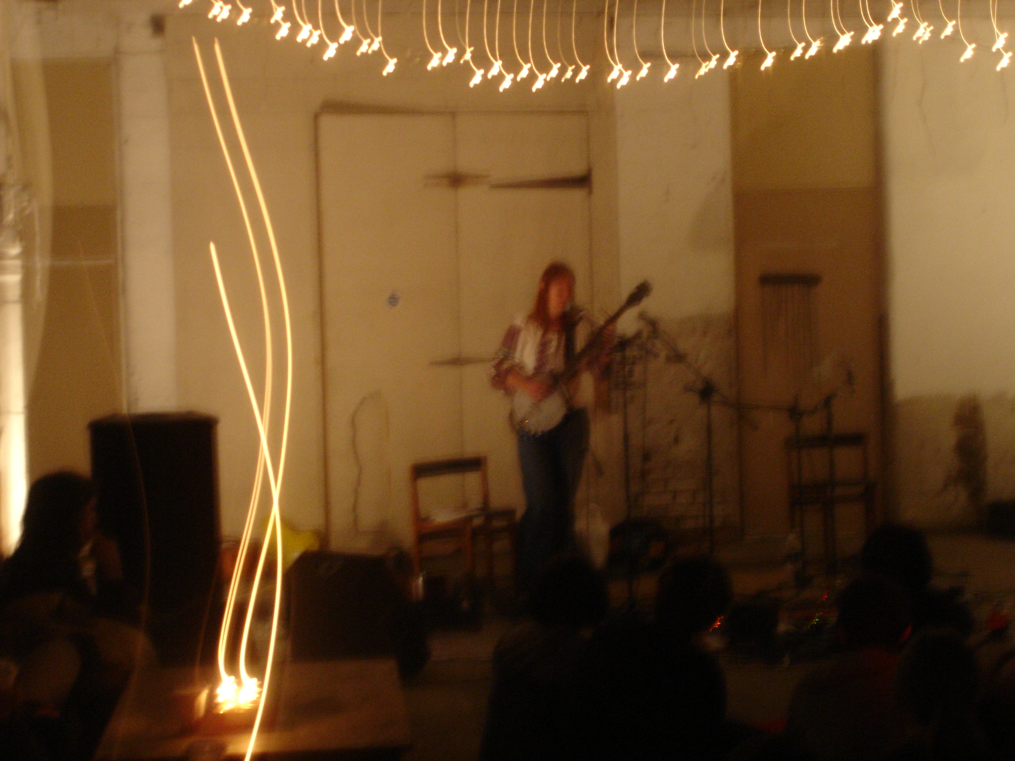 a guitarist performs with strings strung from a ceiling