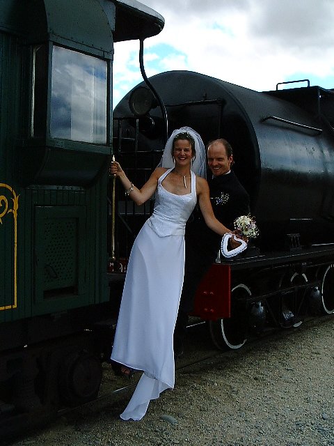 a newly married couple pose with a train