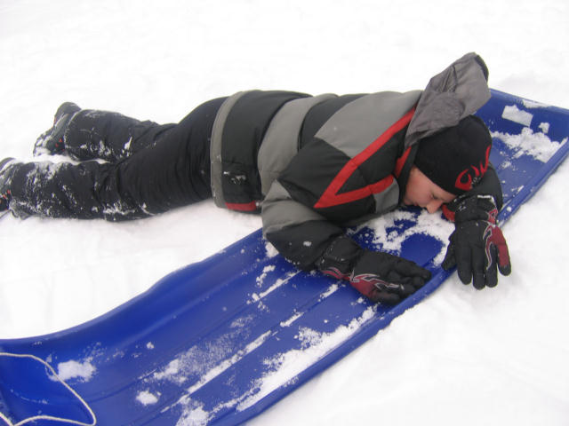 a man wearing winter gear laying on a snowboard