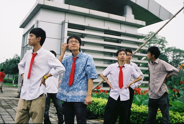 an asian man wearing red neck ties standing between his colleagues