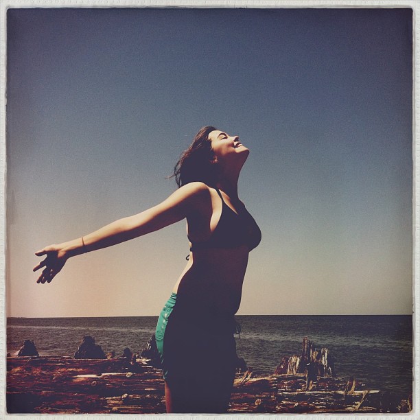 a woman looking up into the air by a beach