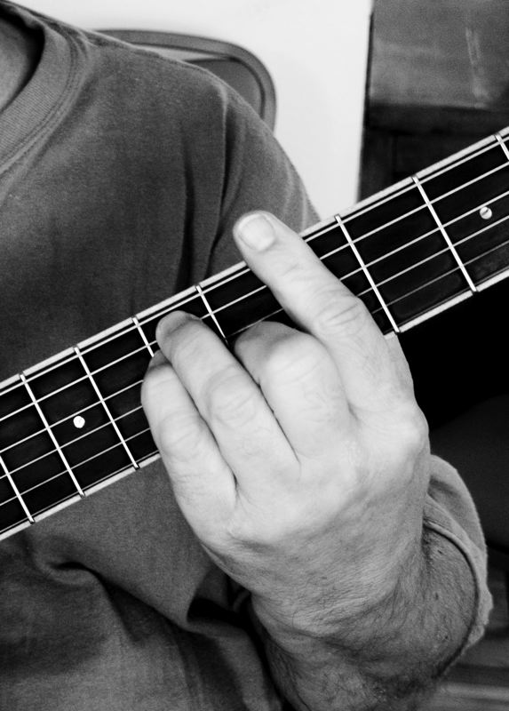 black and white po of man playing guitar