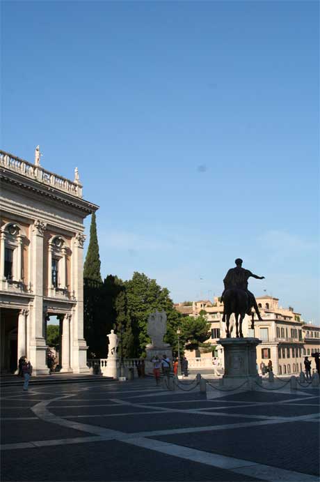 an empty plaza with buildings in the background and statue of a man sitting on a horse