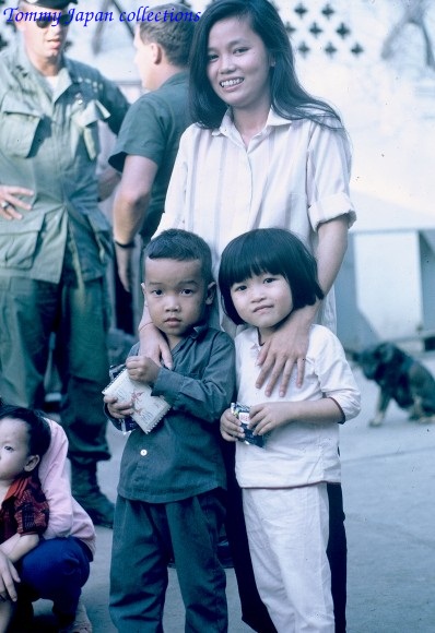 two young children pose for a po while a soldier holds them