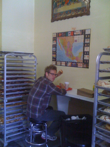 a man sitting at a table with doughnuts and muffins
