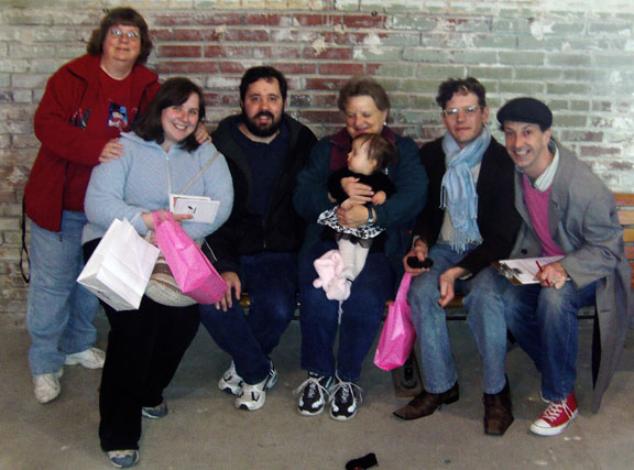 a group of people sitting on a bench together holding bags and purses