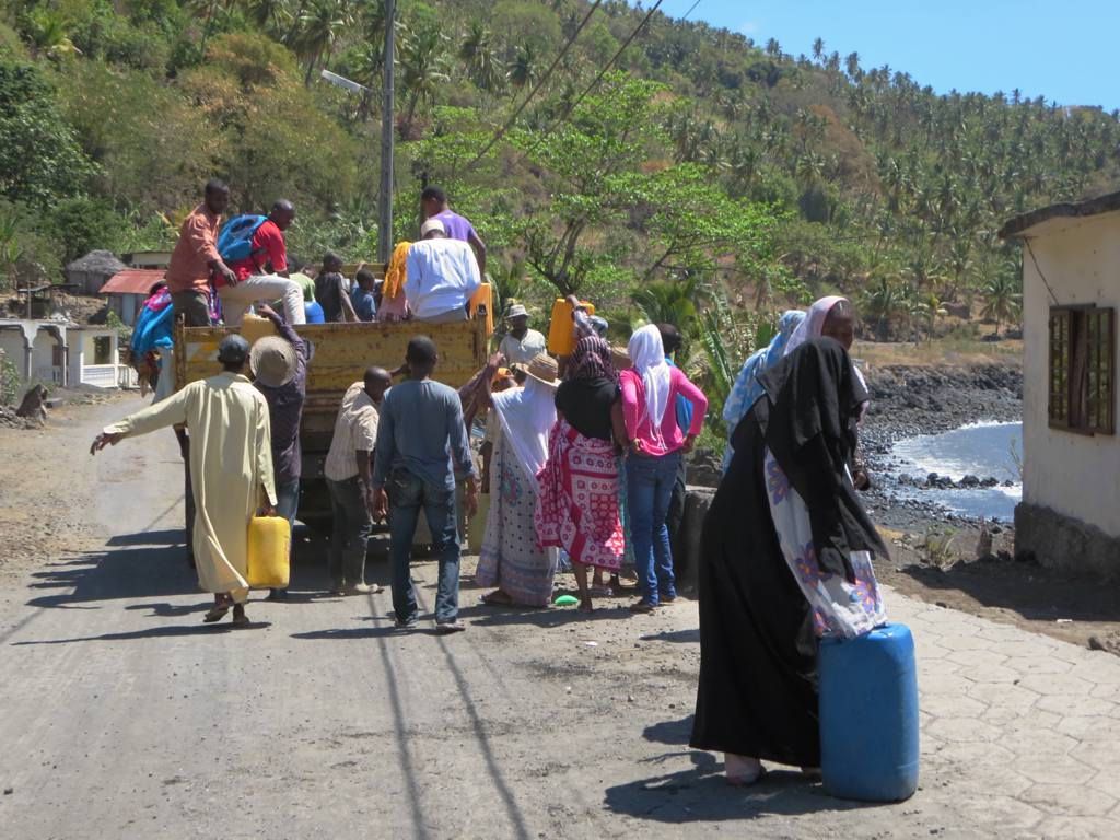 a woman in pink carrying a cart filled with people