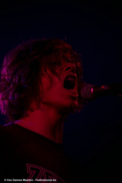 a person standing at a microphone in front of purple lighting