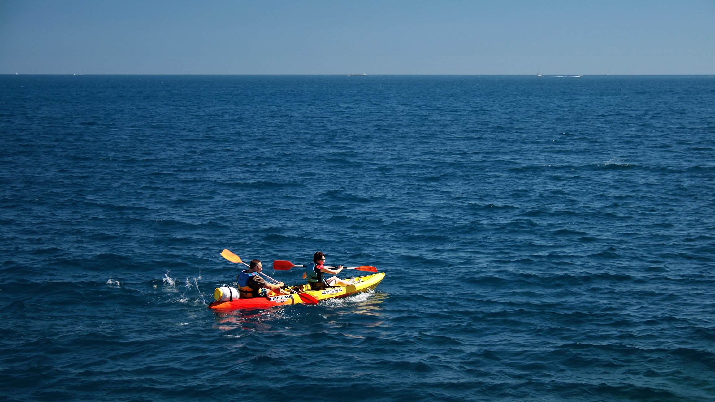 people in an inflatable kayak paddling on a choppy sea