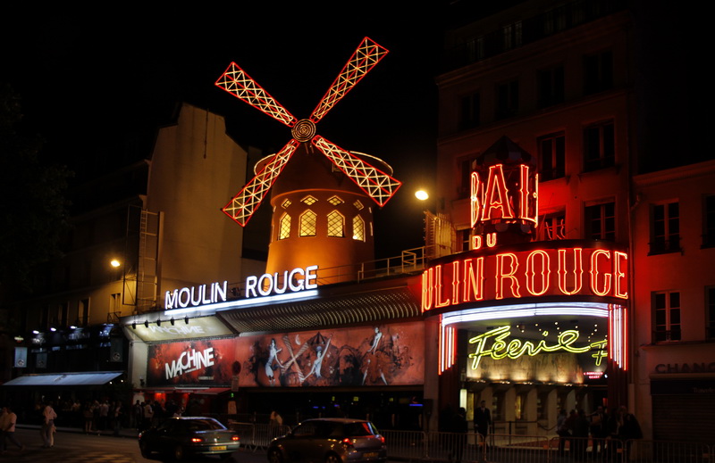 neon signs advertise the shops, while people walk by