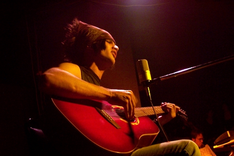 a man playing guitar while sitting in a chair