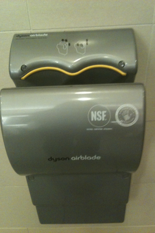 a gray public urinal sits against the wall