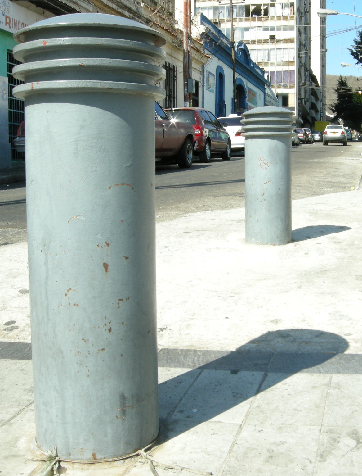 two blue pipes are on the sidewalk near a building