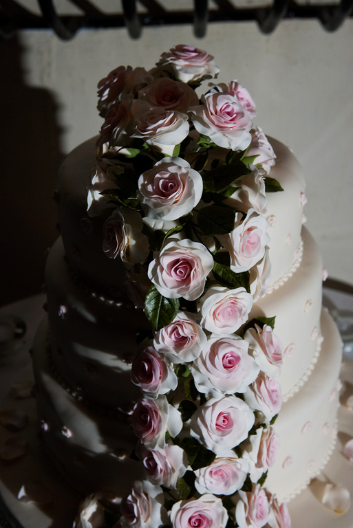 the three layer wedding cake has white and pink roses on it