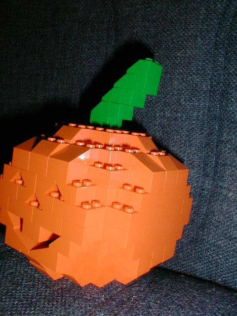 an orange cube shaped like a pumpkin with a green piece