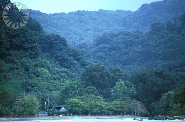 a small house on a lake surrounded by lush green mountains