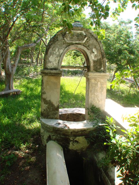 an old arch with a stone base near grass