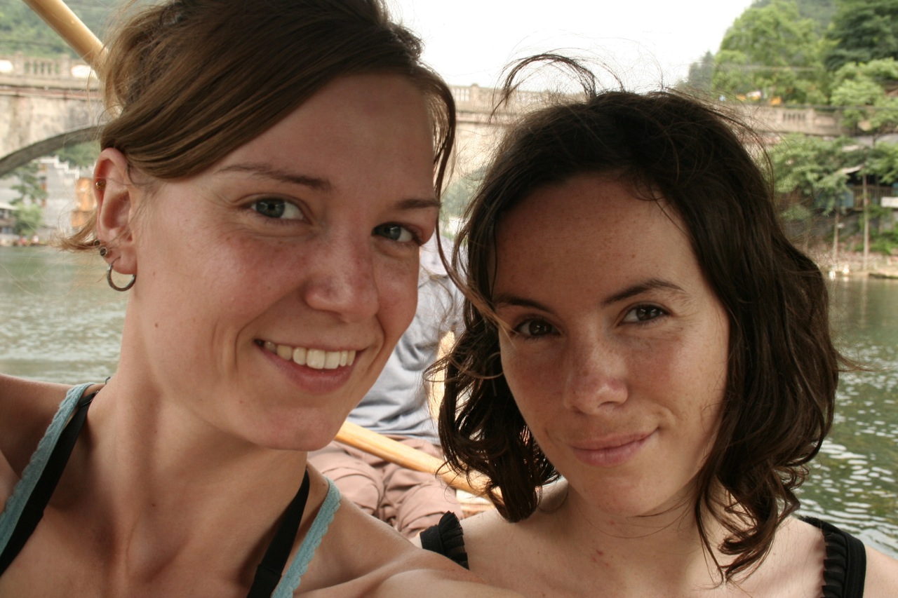 two women are sitting in a boat and posing for the camera