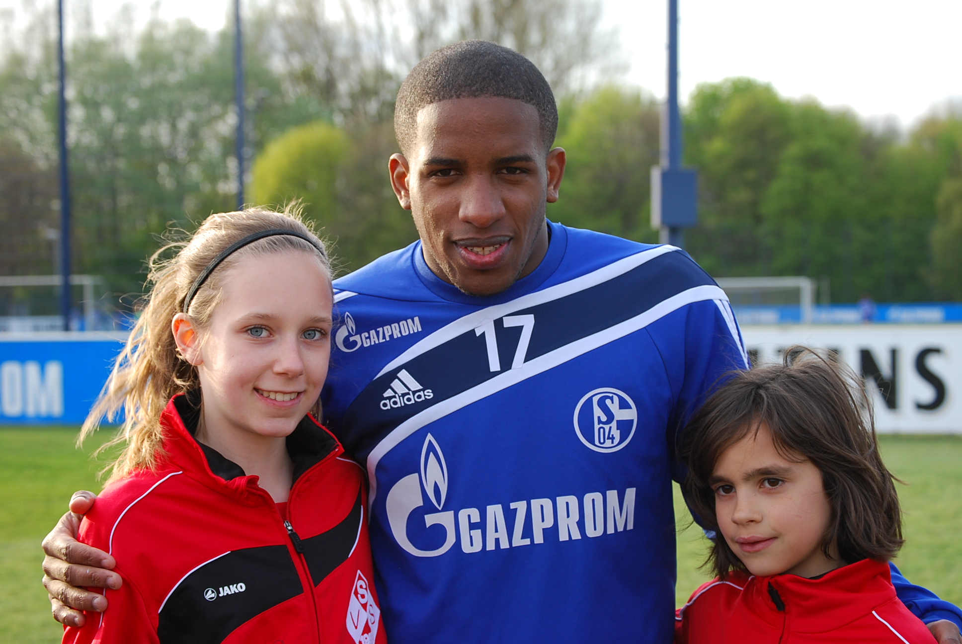 a young man standing next to two girls near a soccer field