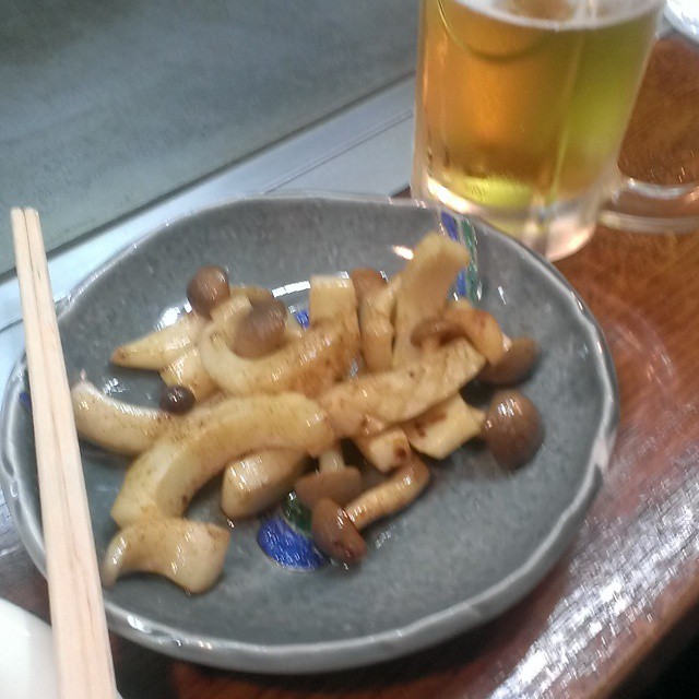 some food and chopsticks on a plate near a beer