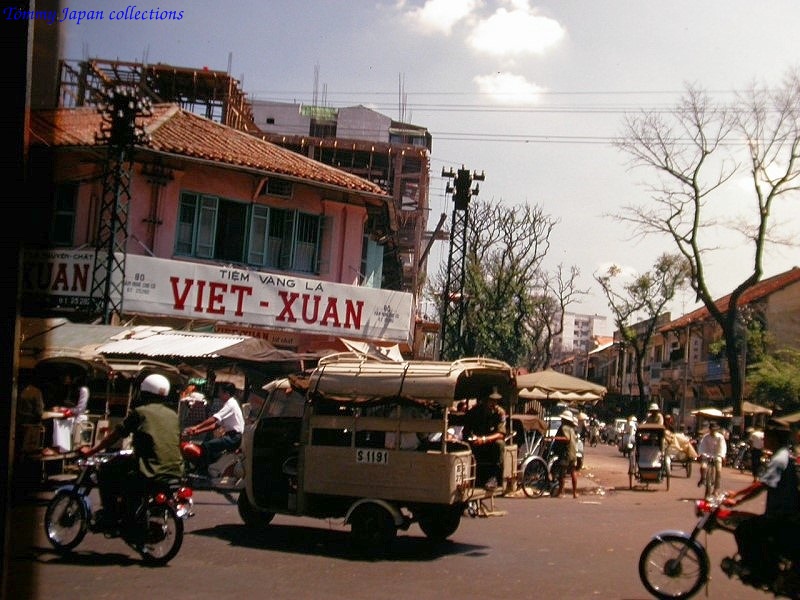 a street filled with people, vehicles and a van