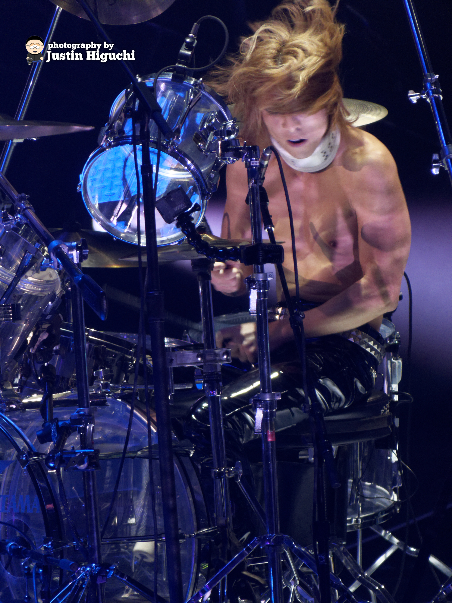 a shirtless man playing drums on stage
