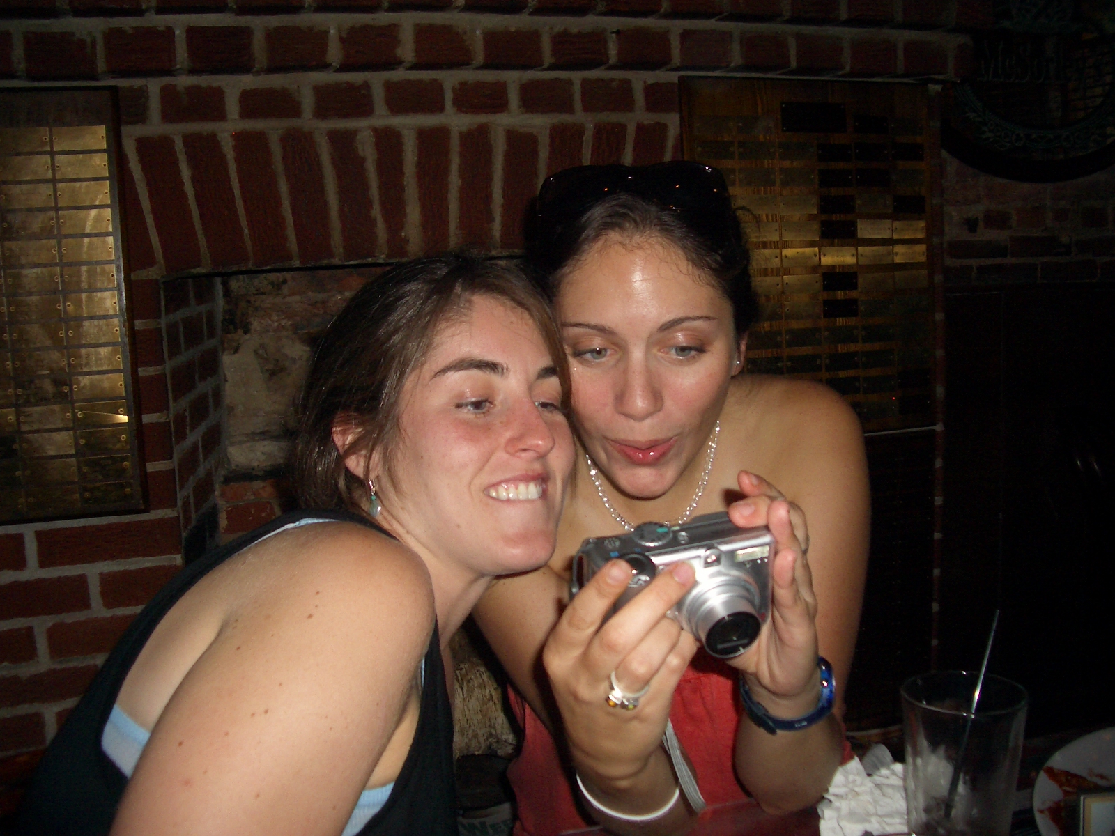 two young women taking pos with a digital camera